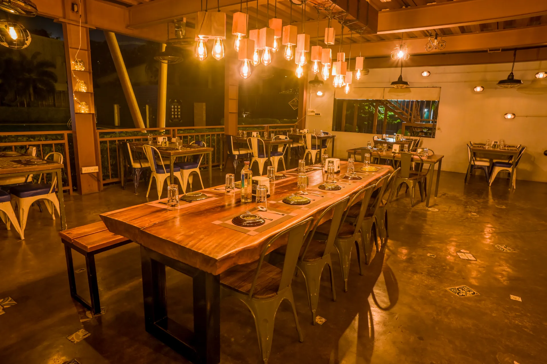 Large wooden dining table and hanging lights at Mysore Union Mysuru