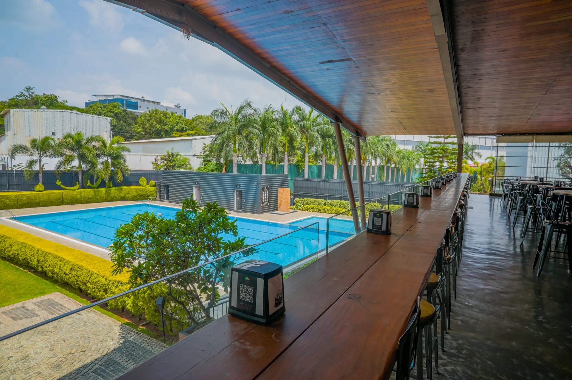 Poolside and outdoor restaurant seating under a wooden canopy at Mysore Union Mysore